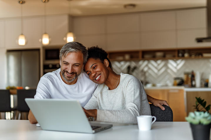 Couple smiling at laptop in kitchen
