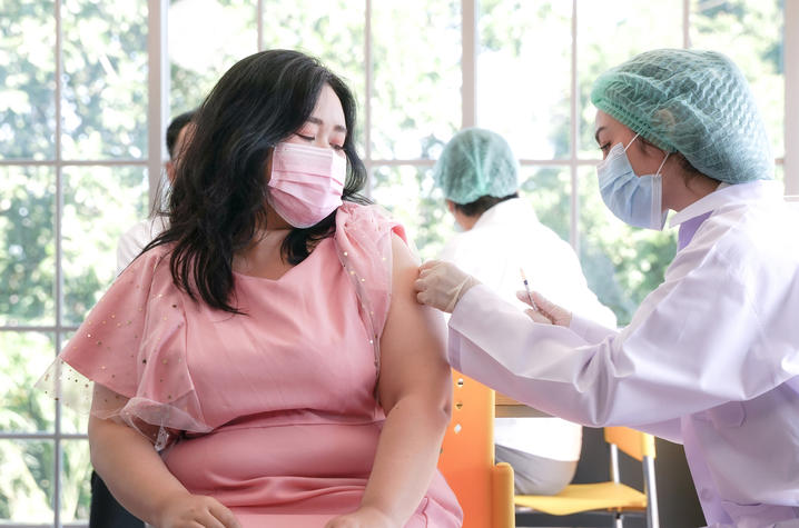 image of woman in facemask getting vaccine.