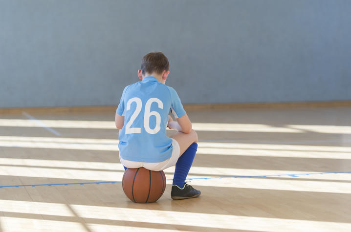 young athlete sitting on a basketball