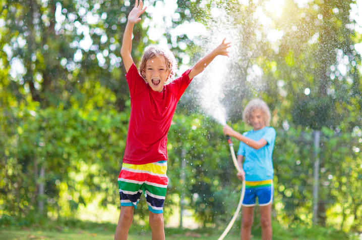 Image of two young kids playing with a water hose in the summer Image of two young kids playing with a water hose in the summer