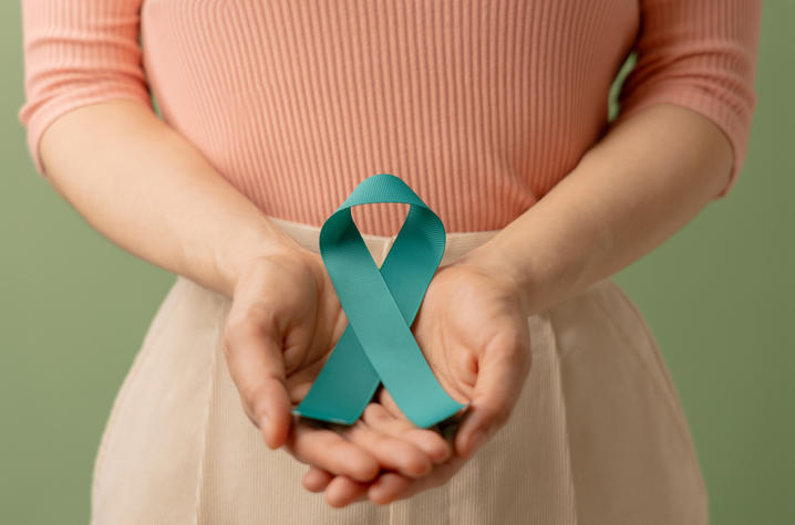 Person holding teal ribbon for ovarian cancer awareness
