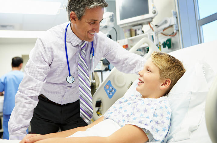 image of doctor leaning talking to boy in hospital bed