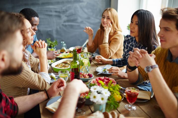 photo of young people around table with food