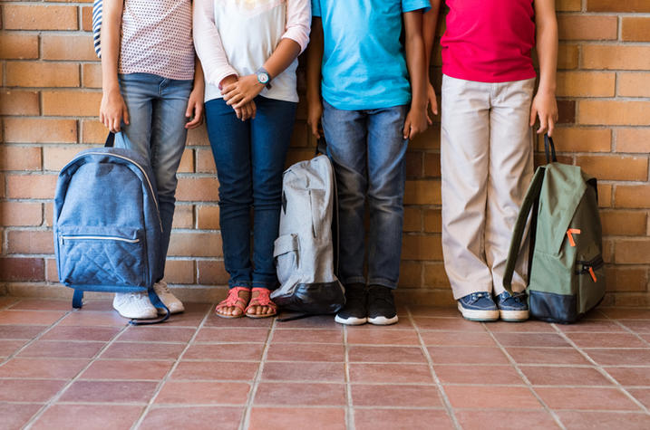 Children holding backpacks. 