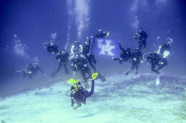 Students holding a UK Flag while scuba diving