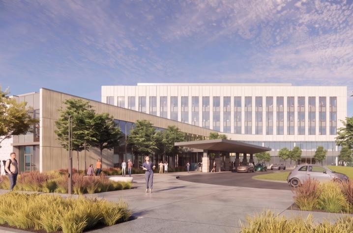 Architectural rendering of a modern multi-story building complex viewed from a landscaped entrance drive. A long white upper level extends above a covered drop-off area, with large windows and lower adjoining structures on either side.