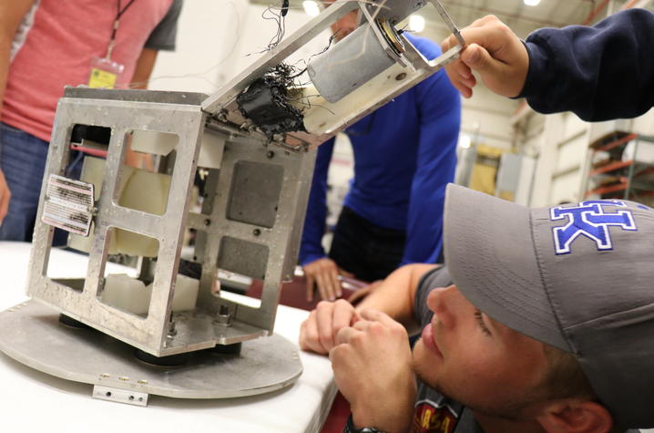 Photo of Devin Sparks examining the capsule ejection module after retrieval. 