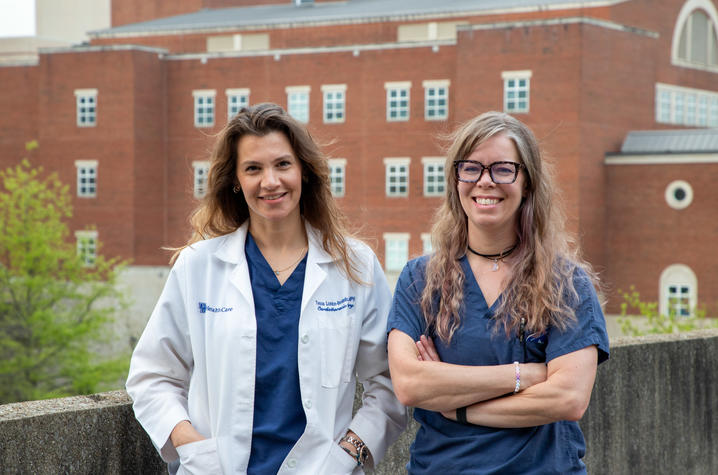image of Dr. London-Bounds in white coat and Amanda Crabtree in blue scrubs standing outside with UK hospital in the background