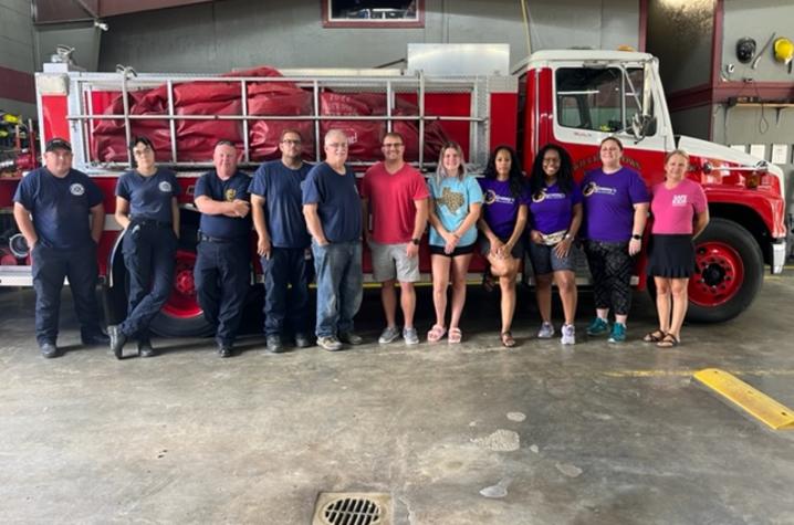 Image of firefighters with teens standing in front of a fire truck