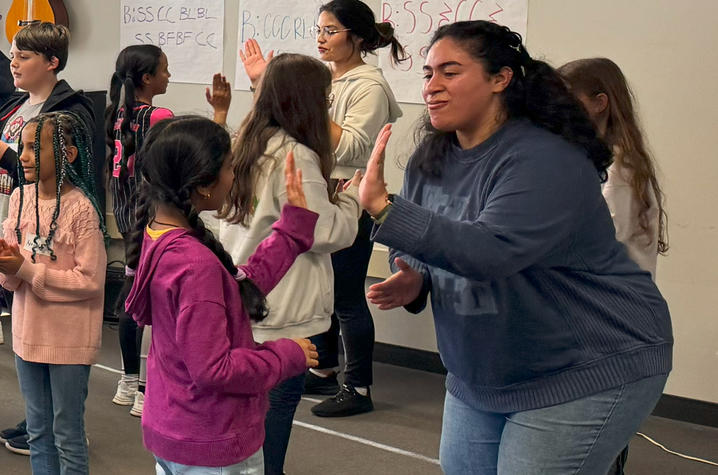 UK music education majors practice rhythm exercises with elementary school students by hand clapping.