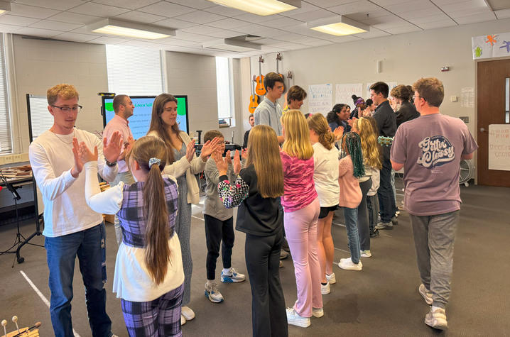 UK music education majors practice rhythm exercises with elementary school students by hand clapping.