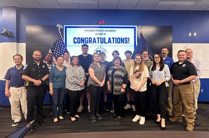 citizens police academy graduates standing and smiling for a group photo