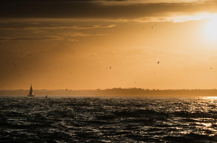 Sailboat at sunset. Sailboat on the water at sunset with golden light reflecting on the waves.