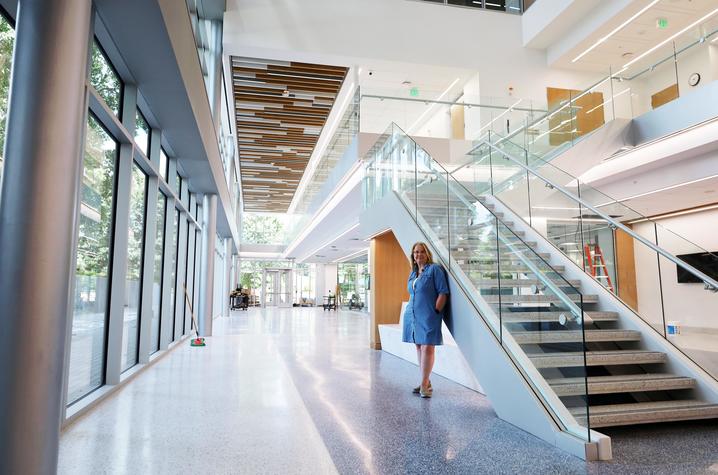photo of Sandy Redmon in Scovell Hall A person stands beside the main staircase in the bright, modern interior of Scovell Hall.
