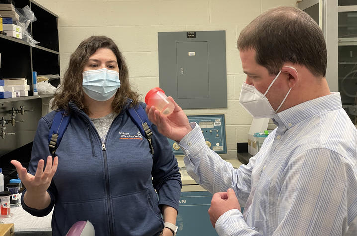 Image of Andy standing in lab holding specimen cup