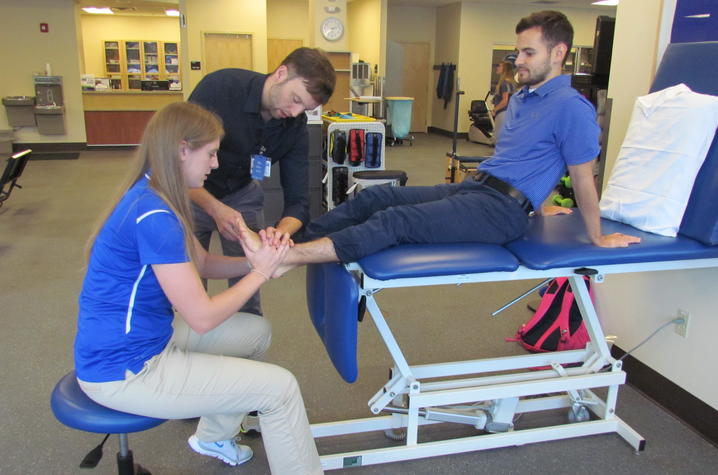 Ryan shows Morgan how to adjust a patient's foot