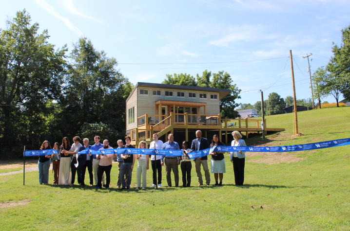A group cuts a ceremonial ribbon in front of the modular emergency housing prototype.
