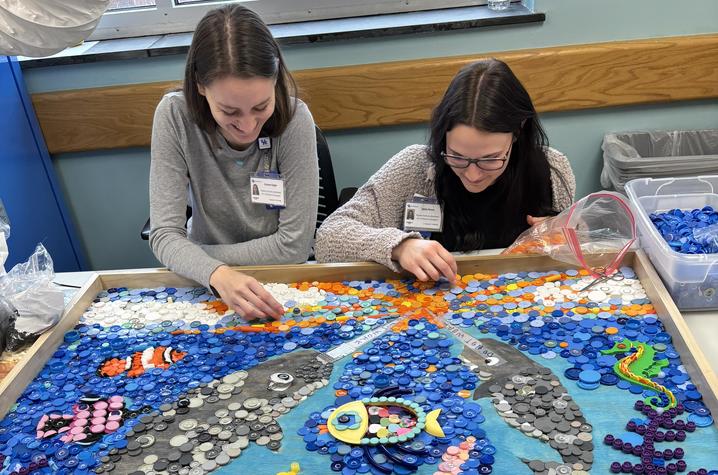 Image of two people glueing plastic to the narwhal art