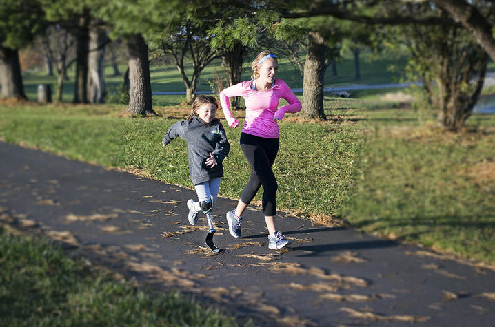 Photo of Carson Swartz running with Katie Eddington, who has a prosthetic leg