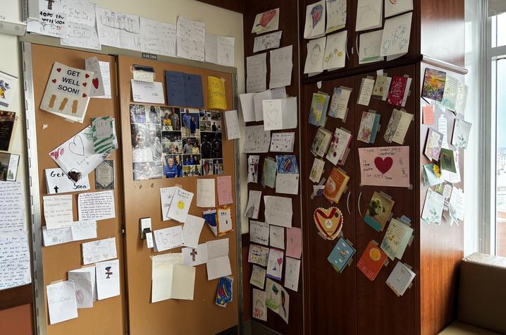 A corner of a room where the walls and doors are covered with numerous handwritten notes, drawings, cards and photos, creating a colorful display of messages and artwork.