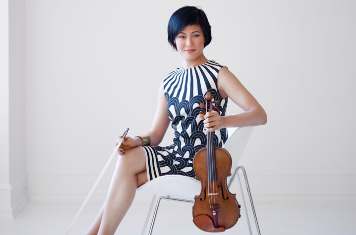 Jennifer Koh seated in chair holding bow and violin