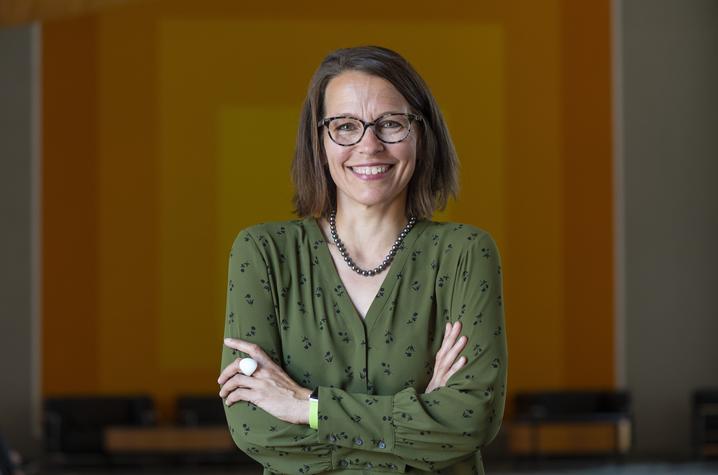 Author Juilee Decker in green shirt with glasses on wood background
