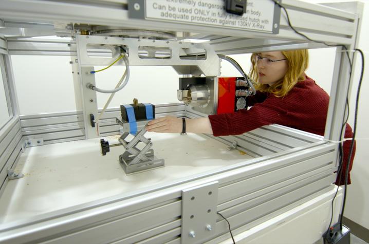 This is a photo of an undergraduate researcher on the Digital Restoration Initiative team, loading a fragment into the scanner. 