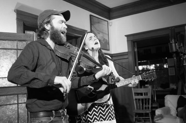 black and white photo of Jesse Milnes and Emily Miller playing fiddle and guitar