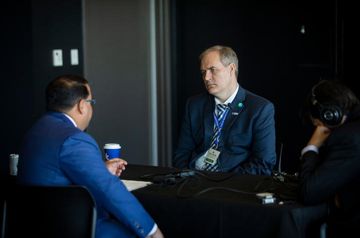 Neal Chatterjee and Rodney Andrews sitting at a table while recording a podcast.