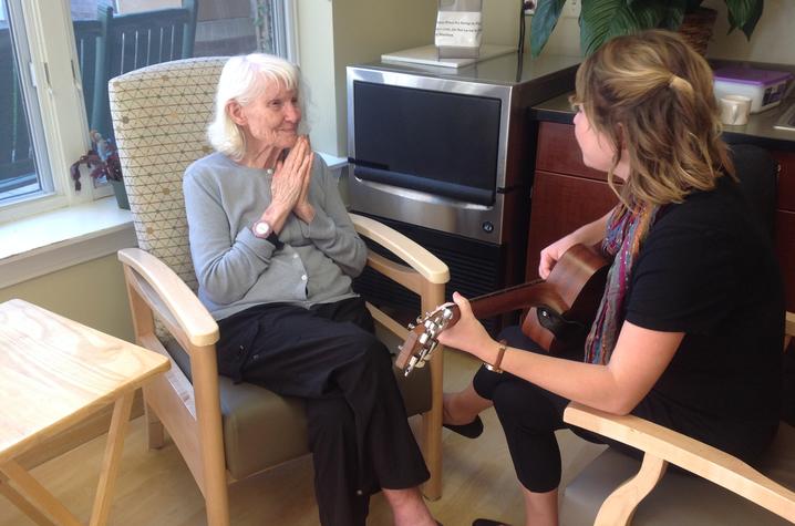 photo of patient listening to music therapist Meghan Ross play guitar at Oaknoll Retirement Residence in Iowa City