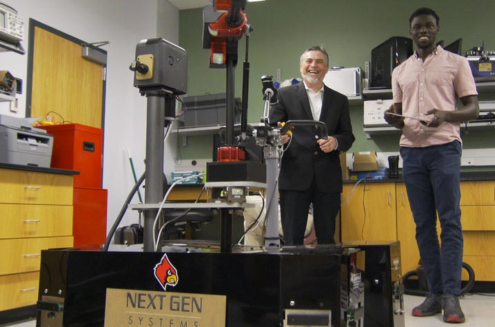 photo of Dan Popa with student, operating robot, at UofL