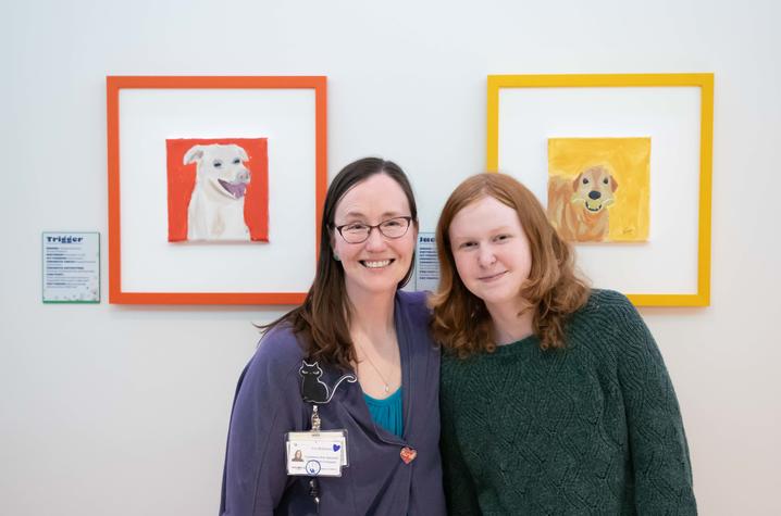 image of Erin and Katie posing in front of dog portraits.