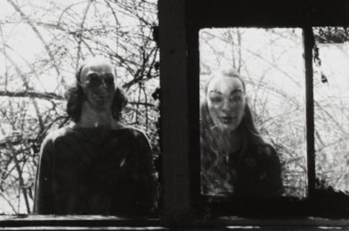 black and white photo of 2 adults in masks in window by Ralph Eugene Meatyard