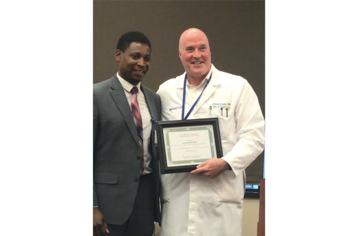 Photo of Chizimuzo Okoli accepting the ESH Research Award from Dr. Andrew Cooley