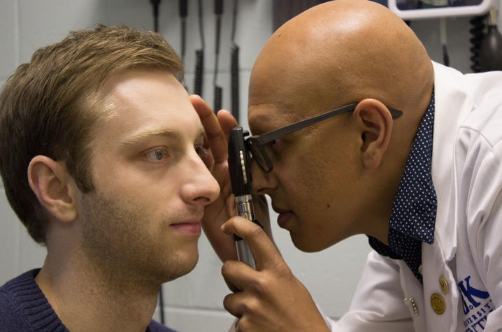 Paras Vora uses an ophthalmoscope to examine a male patient's eye