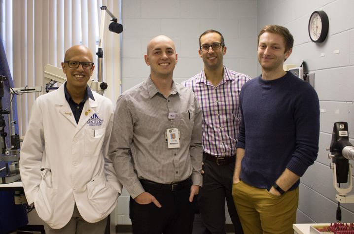 4 men stand in front of medical equipment in a small clinic space