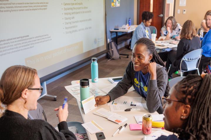 Two students and one professor sitting at a table holding a discussion 