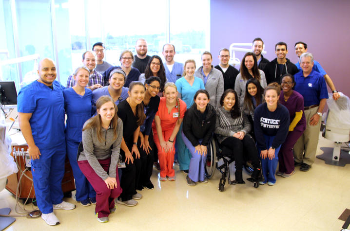 A group of dental students gather together in front of a window