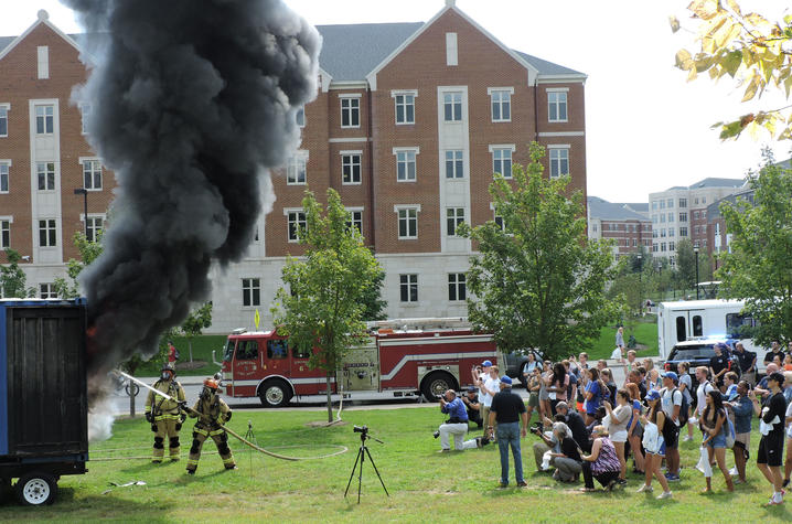 photo of burn demonstration near residence halls with student watching