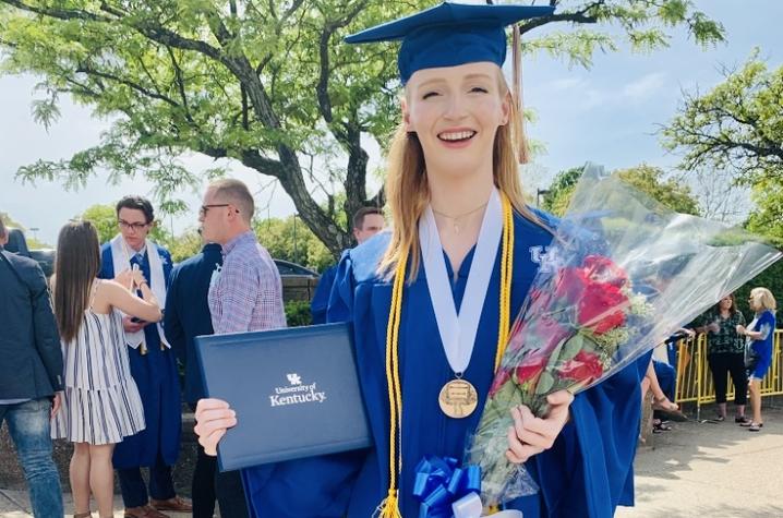 photo of Schuyler Baas in cap and gown with diploma on graduation day