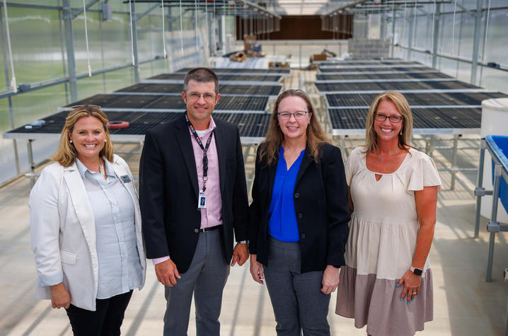 Administrators standing inside greenhouse 