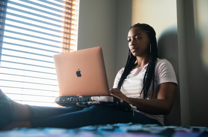 Girl sitting on her bed working on her laptop