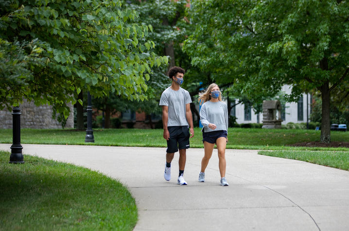 Photo of students walking through campus with masks on