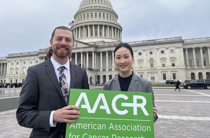 Two people stand in front of the U.S. Capitol building holding an AACR sign, with Subin Kim on the right.