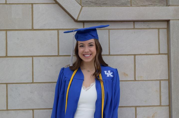 headshot photo of Sydney Sims in cap and gown outside Student Center