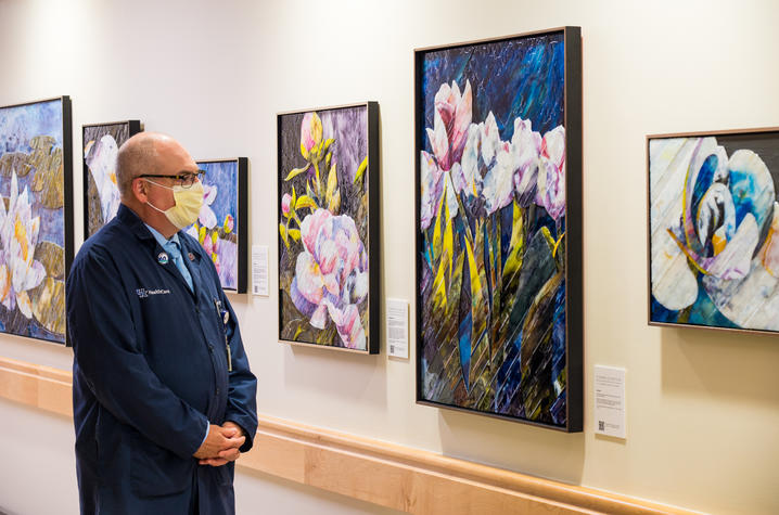 image of man in mask looking at flower painting