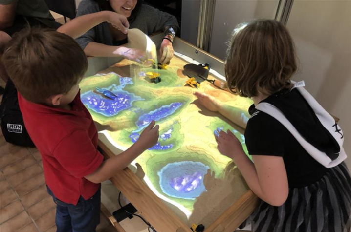 Two Earth Science Week Open House attendees enjoying UK College of Mining Engineering’s augmented reality sand box. 