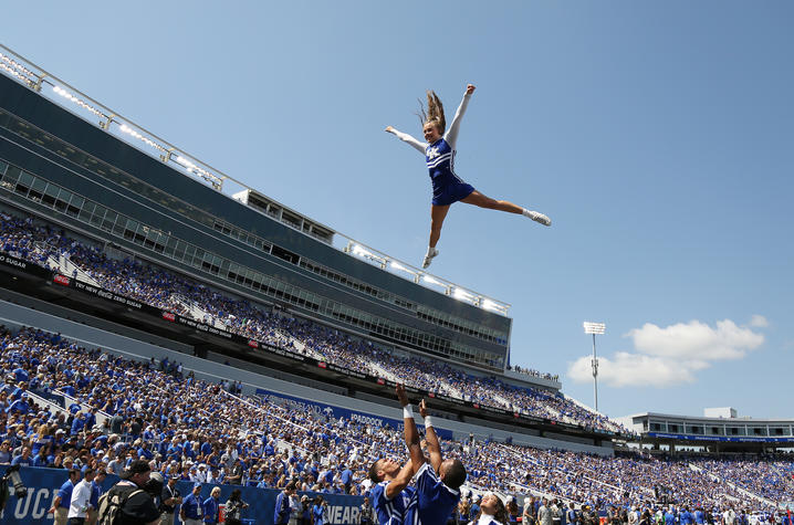 photo of a cheerleader being thrown in the air at a football game at Kroger Field