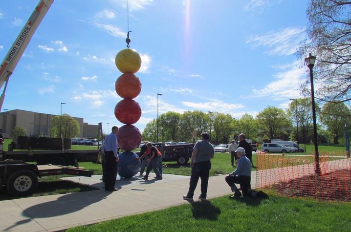 photo of artist Tony Tasset on knee and others at installation of "Mood Sculpture" by Tasset