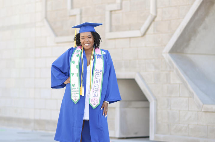 Kymberley Johnson poses in front of the Gatton Student Center in cap and gown